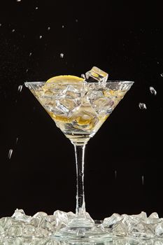 Glass of water, lemon and watersplashes on a black studio background