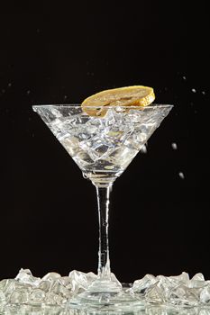 Glass of water, lemon and watersplashes on a black studio background
