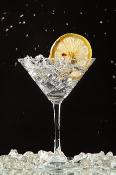 Glass of water, lemon and watersplashes on a black studio background