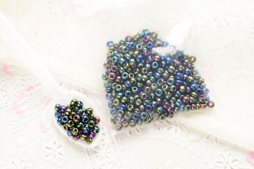 Colorful beads on white fabric surface. Various of shapes and colors to make jewelry
