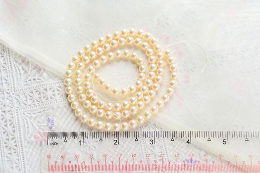 pearl necklace on white fabric background, Close up shot of glass pearls 
