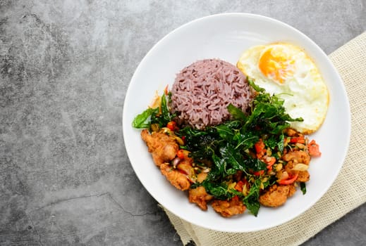 Crispy chicken cooked with green basil, served with steamed rice and fried egg, hot and spicy dish with basil leaves.
