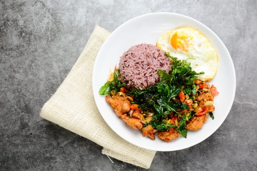 Crispy chicken cooked with green basil, served with steamed rice and fried egg, hot and spicy dish with basil leaves.
