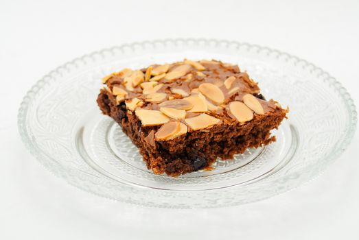 Chocolate brownie with almond topping on glass plated
