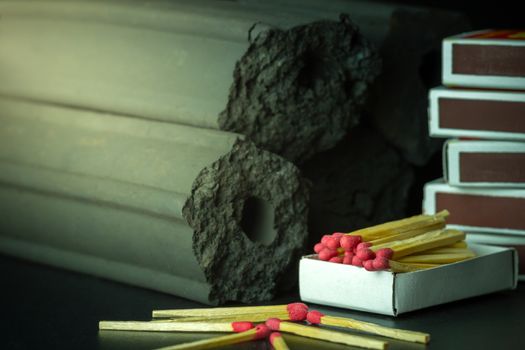 Box of matches and Carbon activated bamboo charcoal on dark background. Concept of fuel for living in the forest. Closeup and copy space.