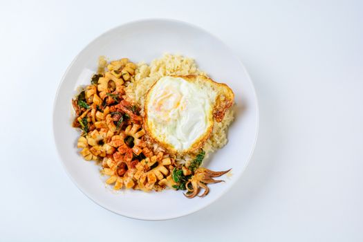 Spicy stir fried squid with basil leaves and chili, Sunny side up egg, served with brown rice. Hot and spicy dish.