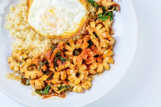 Spicy stir fried squid with basil leaves and chili, Sunny side up egg, served with brown rice. Hot and spicy dish.