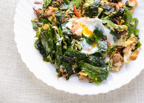 A white plate of delicious Stir-Fried Baegu Leaves or Melinjo with Eggs, served with steamed rice.