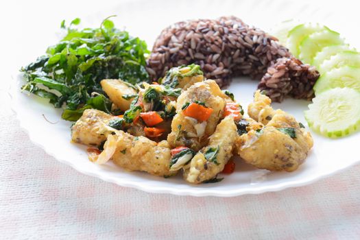 Stir fried fish with chili and basil, served with steamed rice and cucumber, hot and spicy dish.