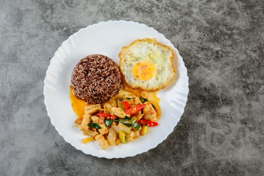 Stir fry chicken sweet onion and peppers, served with brown rice and fried egg on white plate
