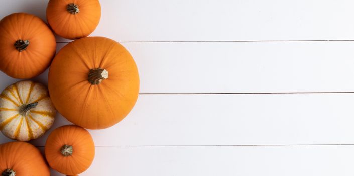 Many orange pumpkins on white wooden background with copy space, autumn harvest, Halloween or Thanksgiving concept