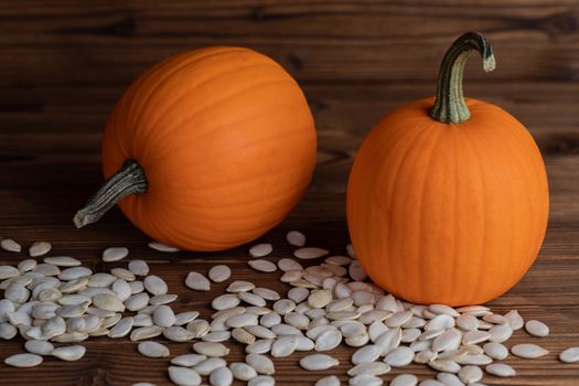 Fresh orange pumpkins and pimpkin seeds close-up on wooden background