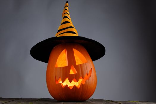 Jack O Lantern Halloween pumpkin with witches hat on wooden background