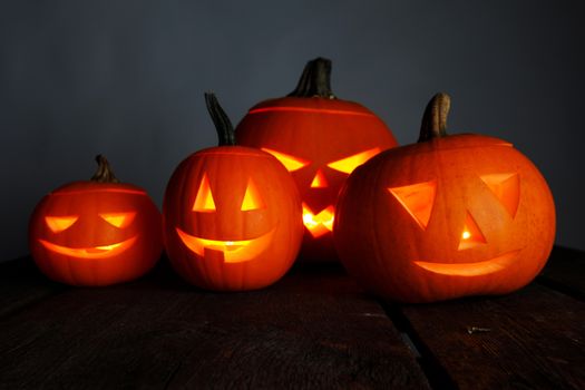Glowing halloween pumpkin head jack o lantern with candles inside on wooden background