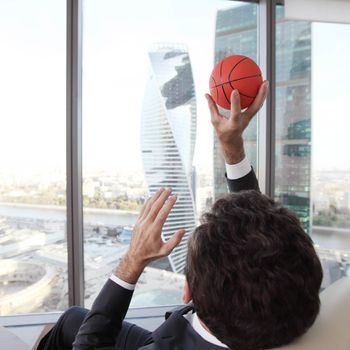 Business man playing with a basketball at the office