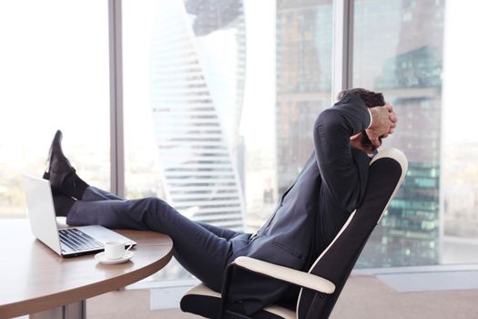 Businessman relaxes sitting in the office and looking in window