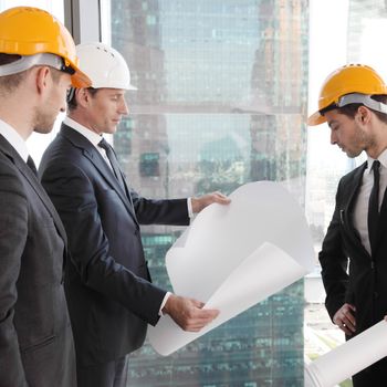 Businessmen and architect team in office planning construction project with office buildings