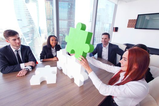 Group of business people assembling jigsaw puzzle and represent team support and help concept in office