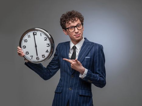 Funny businessman with wall clock pointing checking the time