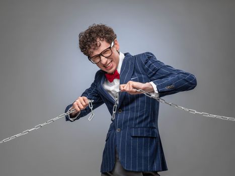 Funny businessman breaking the chain by hands for liberation as a symbol of work captivity