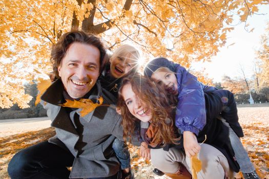 Happy smiling family of parents and children having fun hugging in autumn park
