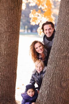 Happy family of parents and children playing in autumn park