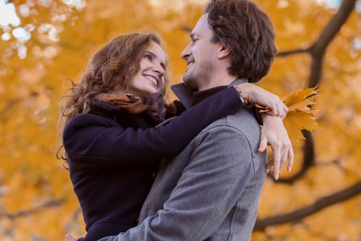 love, relationship, family and people concept - couple with maple leaves hug in autumn park