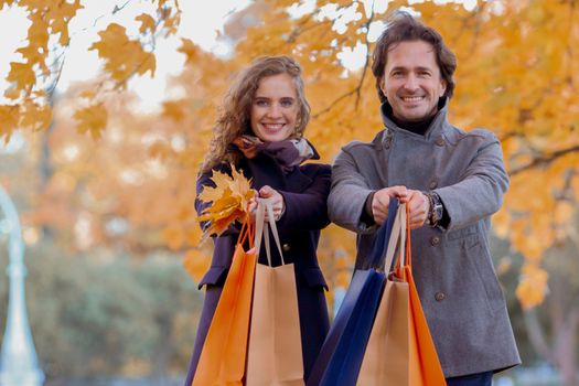 Couple with shopping paper bags in fall forest , autumn sale concept
