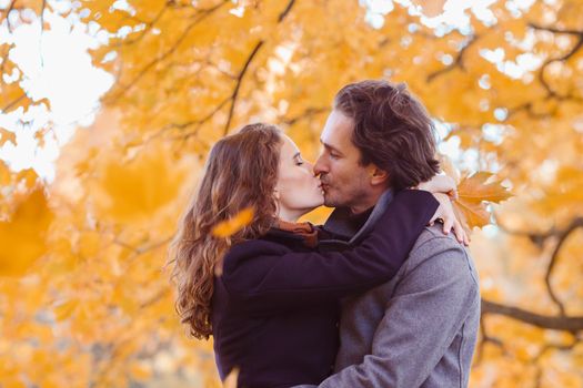 love, relationship, family and people concept - couple with maple leaves kissing in autumn park