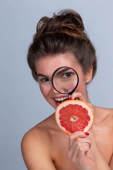 Woman watching grapefruit slice with a magnifying glass