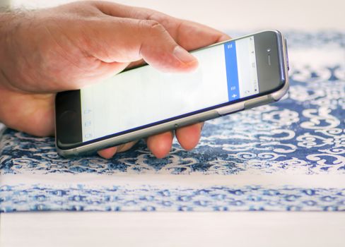 Male hand checking mail using a smartphone by touching the screen with fingers