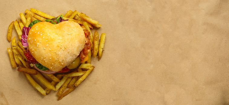 Heart shaped hamburger and french fries, love burger fast food concept, on brown paper background, top view