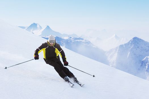 Alpine skier on piste running downhill in beautiful Alpine landscape. Blue sky on background. Free copy space for text