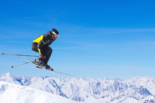 Jumping skier at jump with alpine high mountains