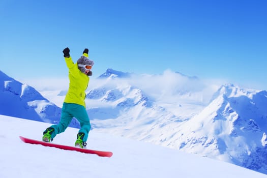 Girl snowboarder running down the slope in Alpine mountains. Winter sport and recreation, leisure outdoor activities. Image of excited screaming young woman enjoyment concept