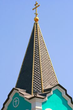 Close-up of the bell tower with a cross against the sky.