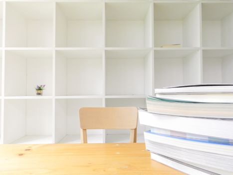 Modern wooden white bookshelf with some books on wood table, library background indoors, clean and modern decoration.
