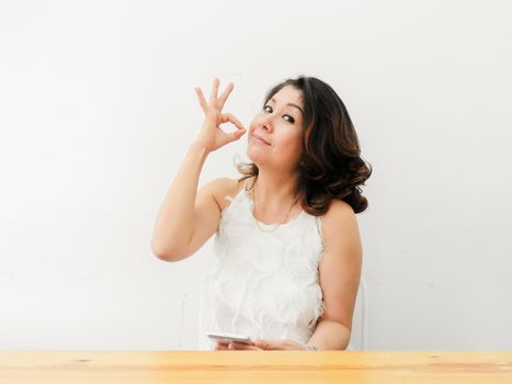 Beautiful woman showing OK hand sign smiling happy against white background.
