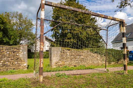 Rusty soccer goal a little rusty on a lawn in front of a wall in the region of Virton in Belgium