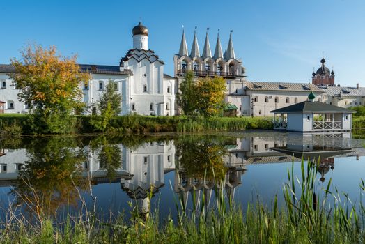 The bell tower of the Tikhvin Assumption (Bogorodichny Uspensky)   Monastery with a reflection in the pond. Tikhvin, Russia