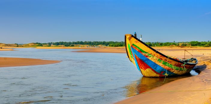 Traditional colorful fishing boat anchored at the confluence of Mahendra Tanaya river and Bay of Bengal, copy space