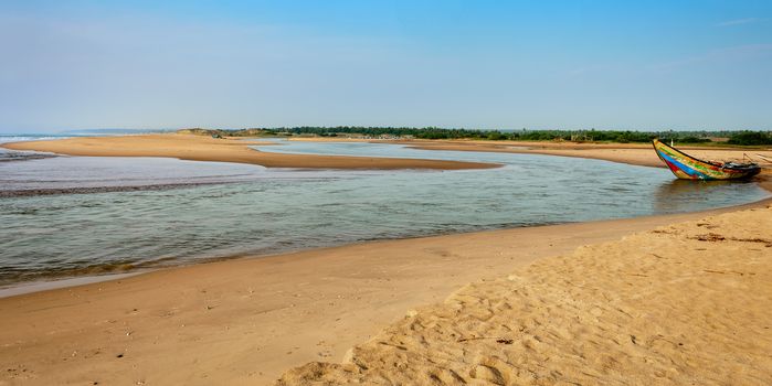 Traditional colorful fishing boat anchored at the confluence of Mahendra Tanaya river and Bay of Bengal, copy space