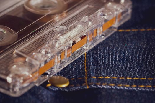 Cassette tape audio on jeans fabric in darkness. Concept of vintage 90s music player.