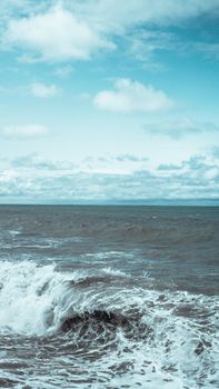 A breaking wave and stormy sea in a vertical panorama format.
