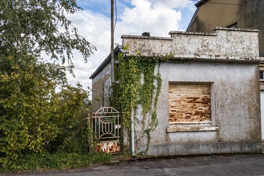 Small abandoned house with a rusty gate gate in the small town of Virton in the province of Luxembourg in Belgium