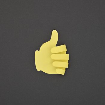 Paper made yellow LIKE hand gesture sticker over grey background