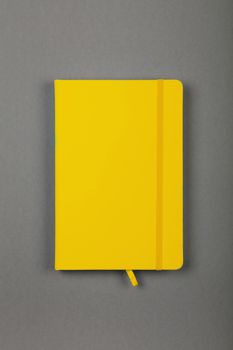 One closed yellow faux leather cover notebook on grey paper background, flat lay, directly above