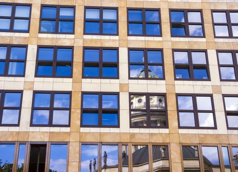 Cloudy sky and church reflected in the windows of a high building.