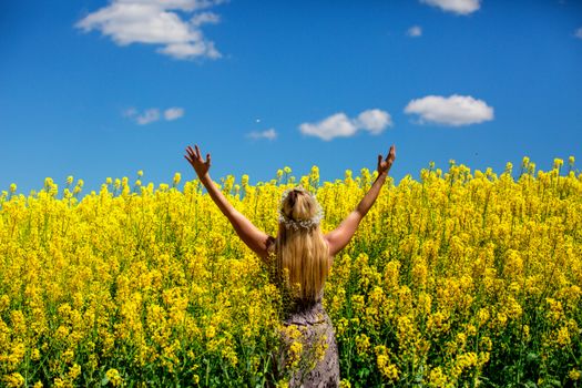 Woman in a field of golden yellow flowers of Canola