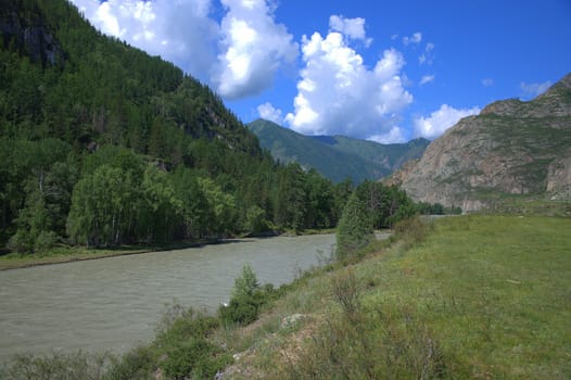 The calm flow of the river through the valley at the foot of the mountains. Altai, Siberia, Russia.